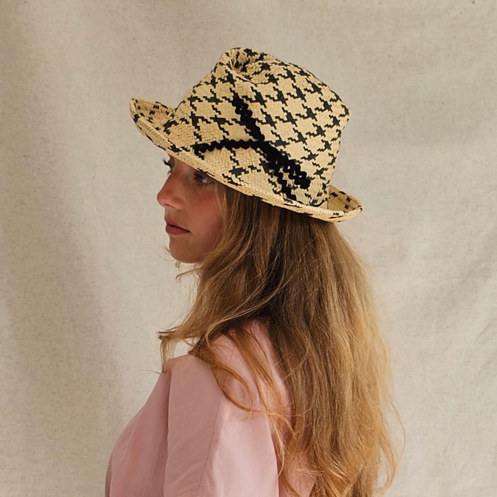 Natural and black check straw trilby with beautiful bow embellishment, side angle view.