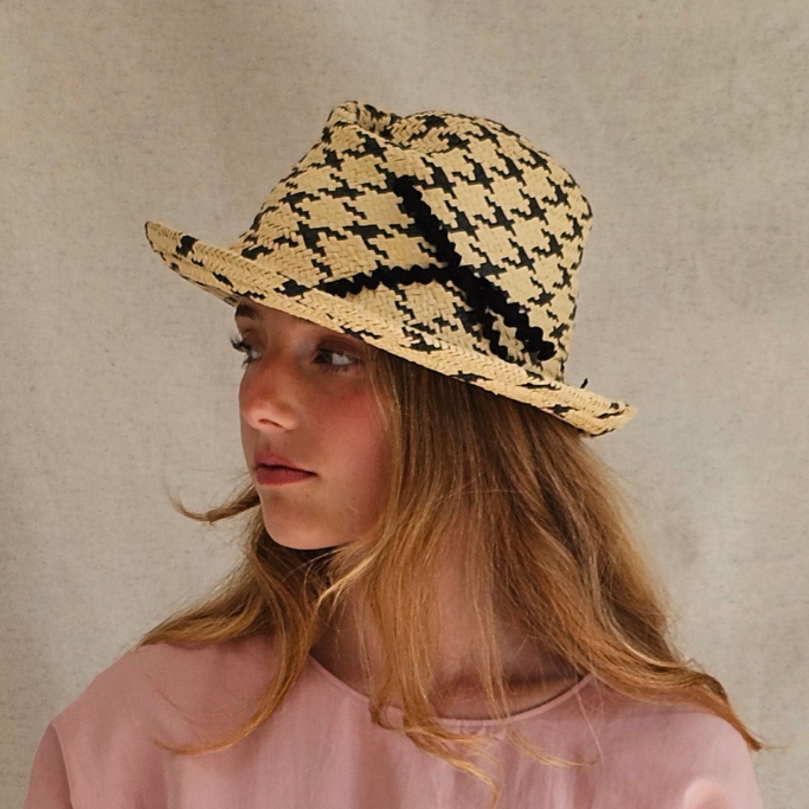 Natural and black check straw trilby with beautiful bow embellishment, side view.