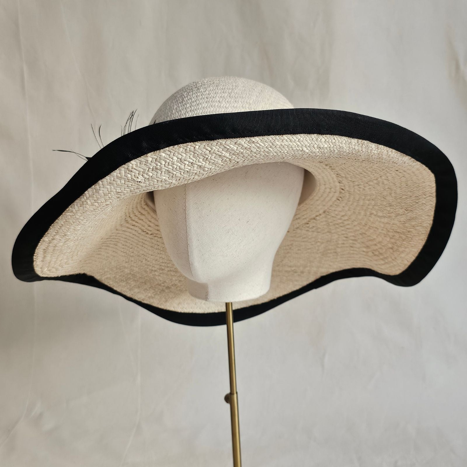 natural straw sunhat with beautiful black flower and rim, left view.