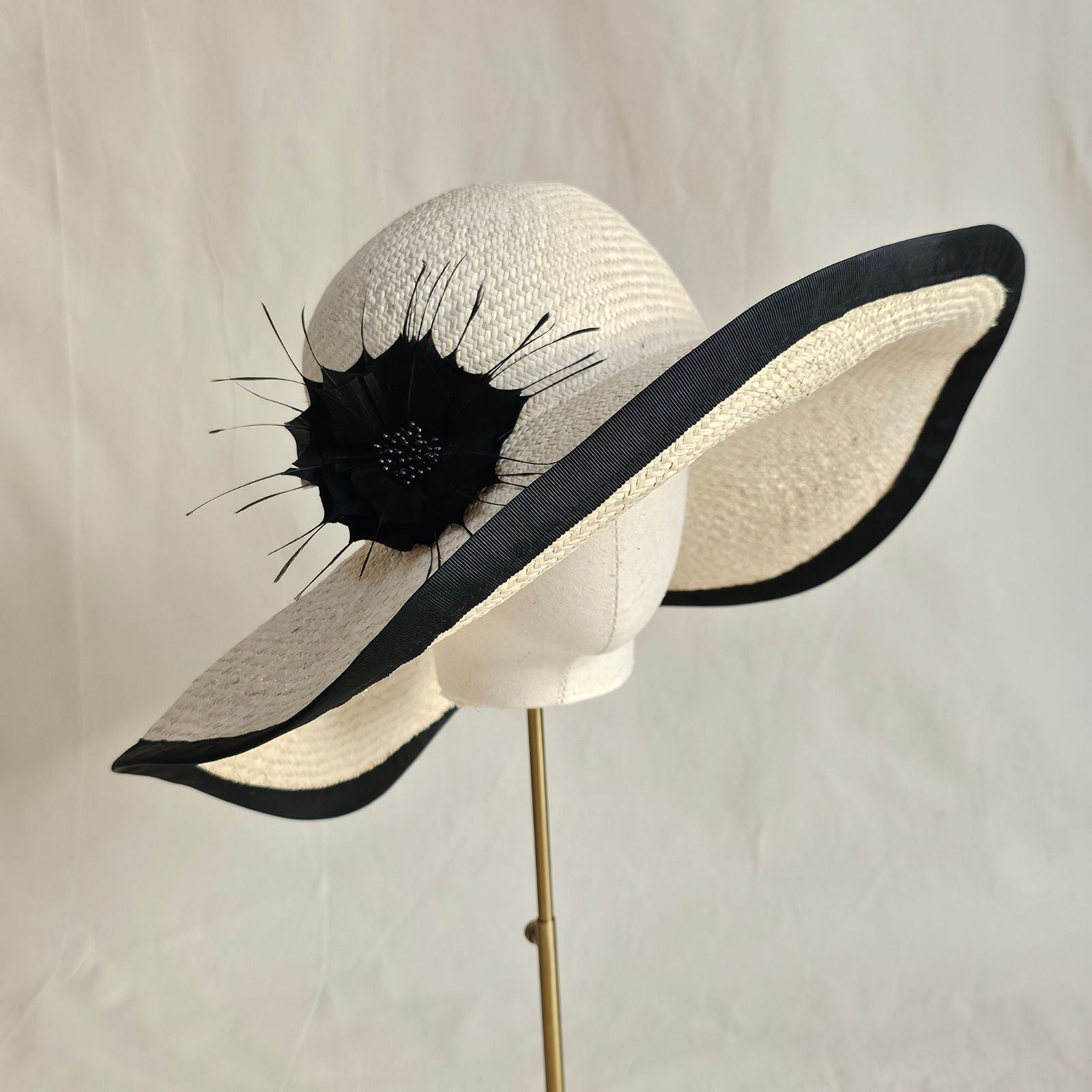 natural straw sunhat with beautiful black flower and rim, side view.