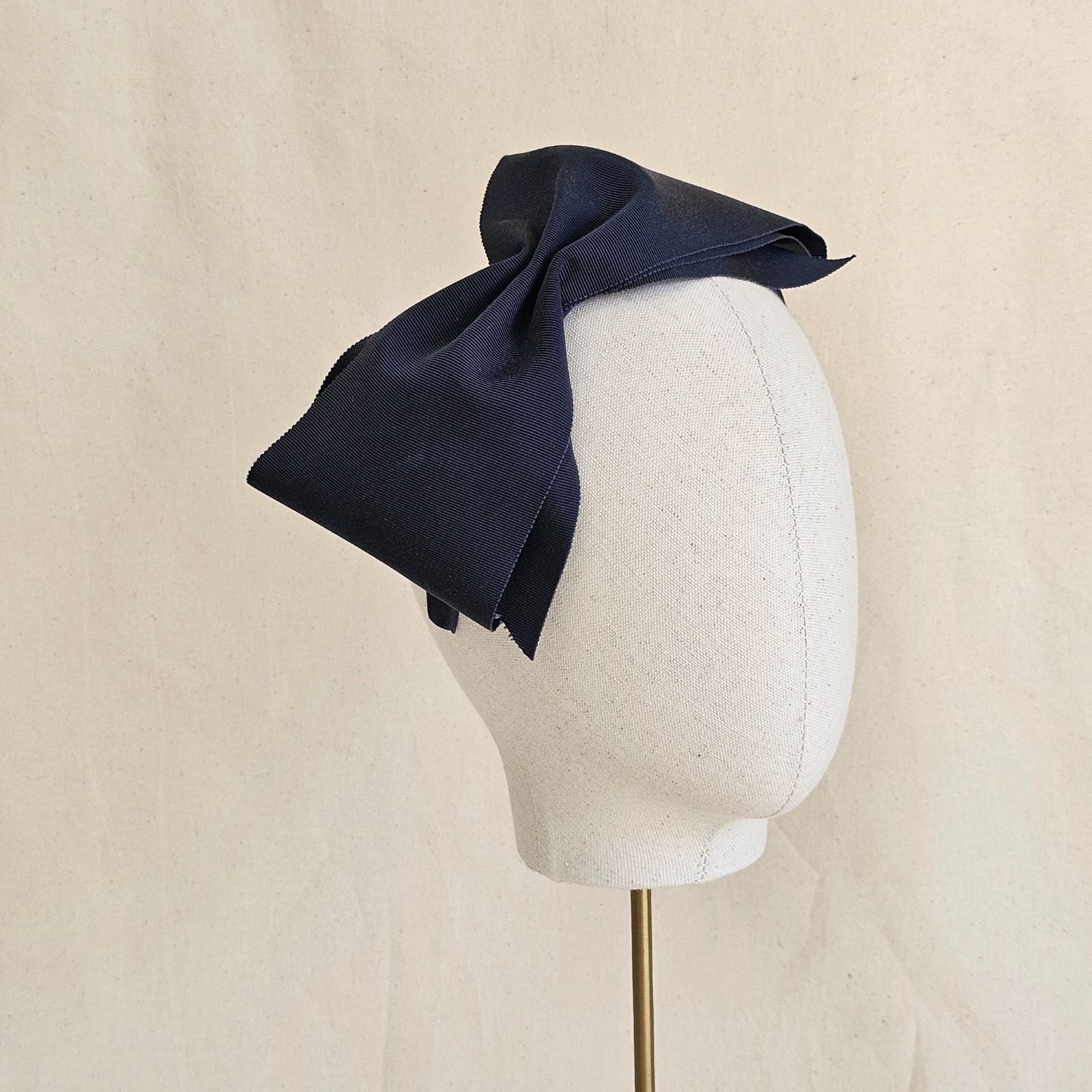 Navy wide petersham bow on a headband, angle view.