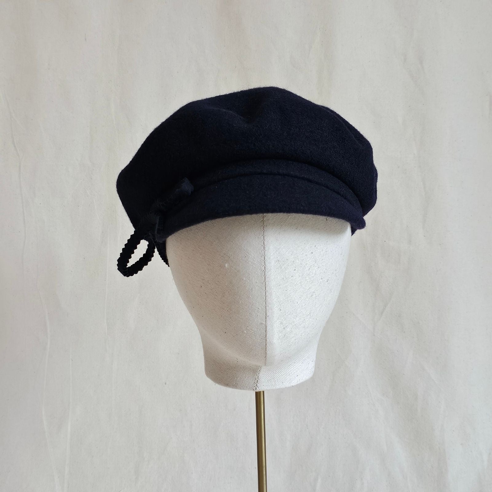 Navy wool cap with bow embellishment, front view.