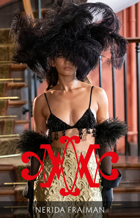A model wearing an oversized black feather hat by Nerida fraiman at the Azzopardi show with 'NERIDA FRAIMAN' logo and text at the bottom.