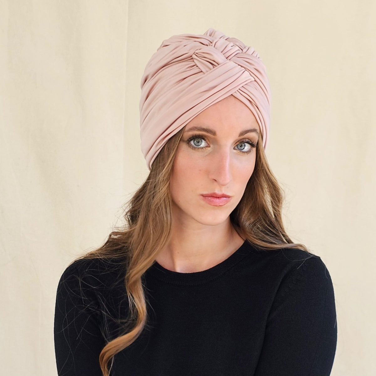 Nude silk jersey turban with integrated braiding, worn on a model.