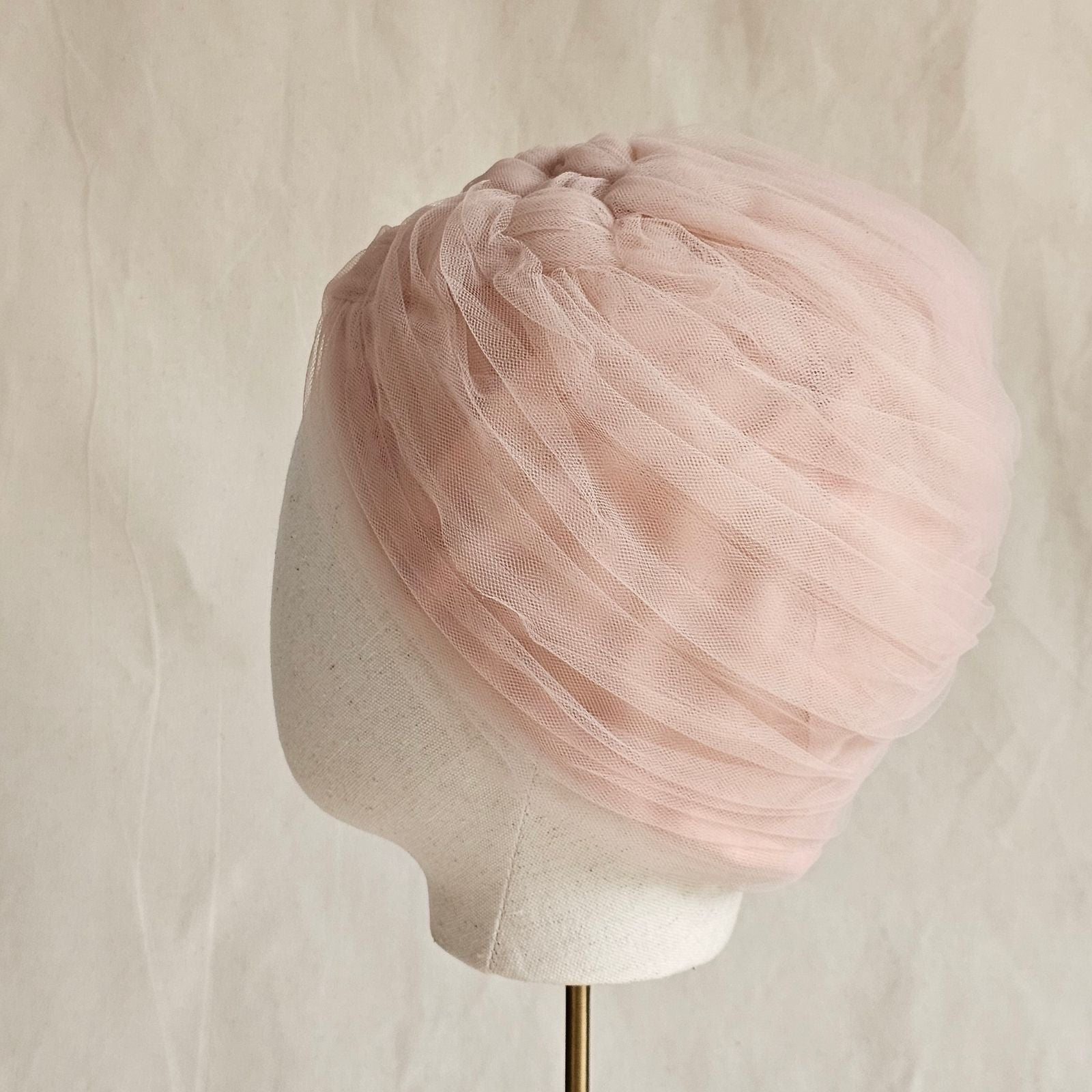 Nude tulle turban braided intricately, side view.