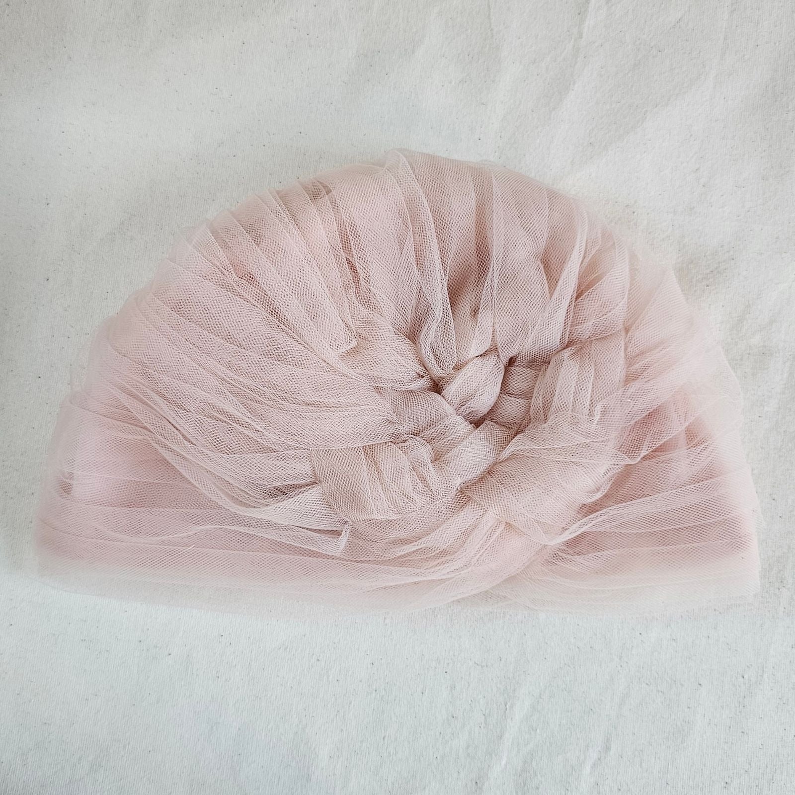 Nude tulle turban with intricate braid embellishment, top view.