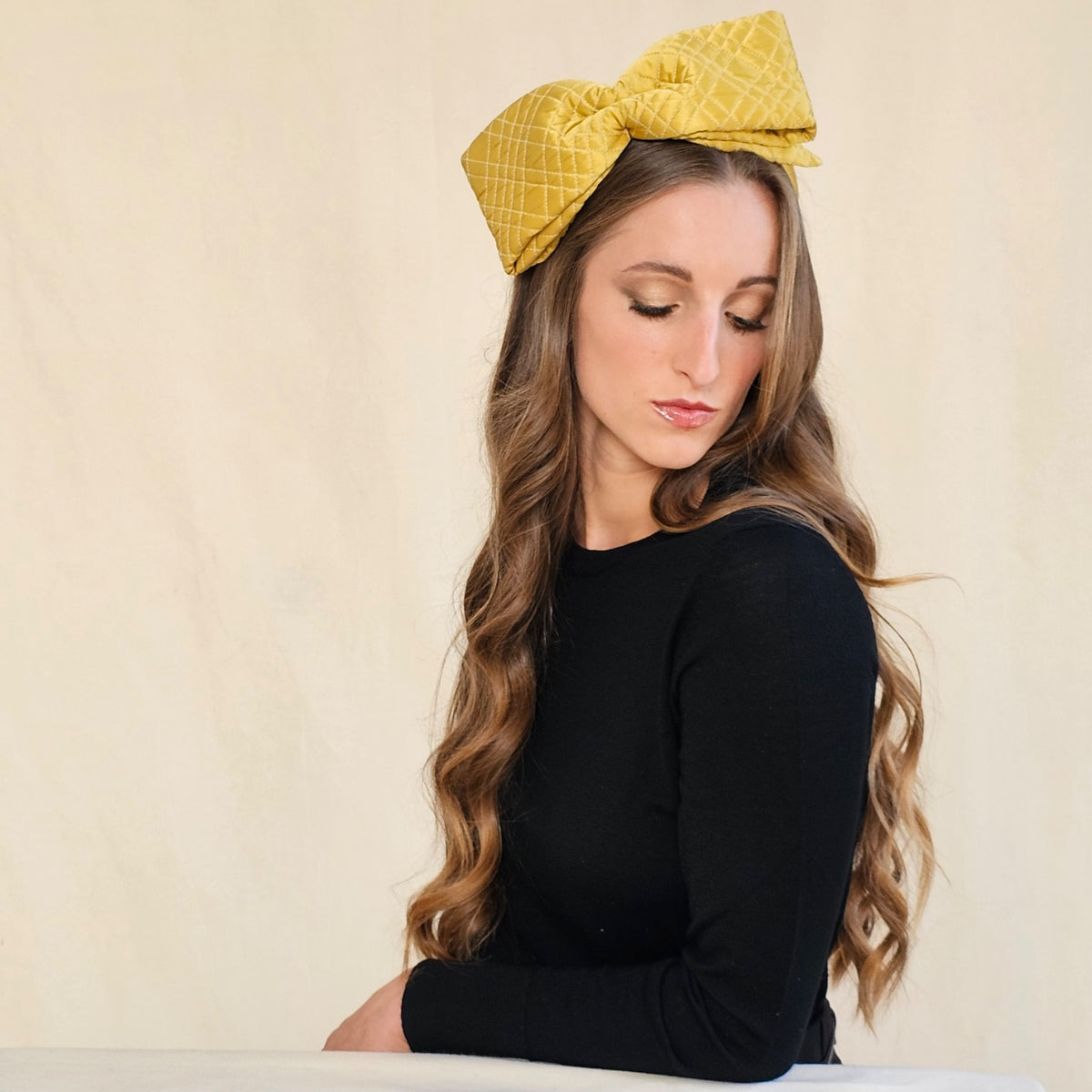 Ochre quilted silk bow headband on a seated model, showing its
width.