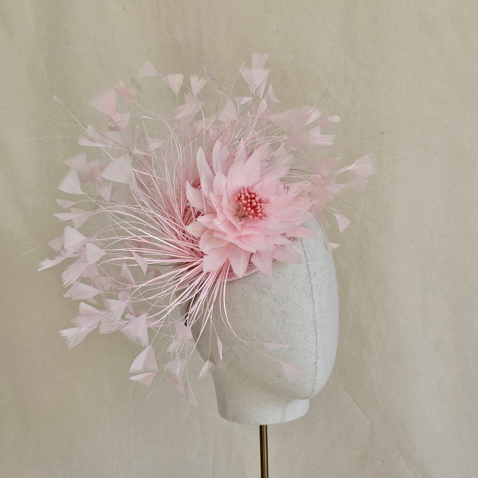 Pink feather fascinator with feather flower, side view.