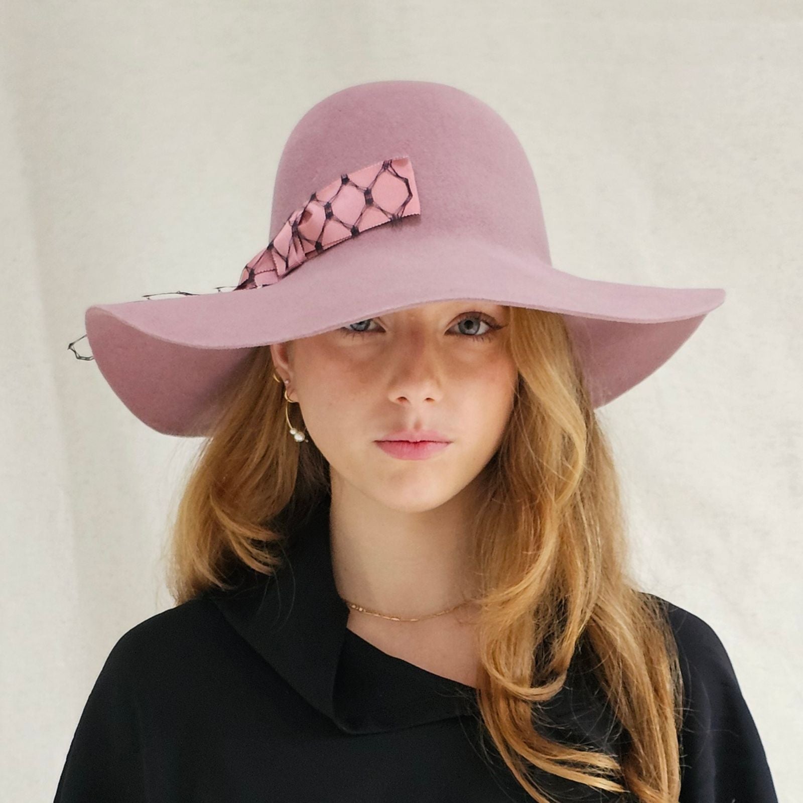 Pink felt 1970s floppy hat with beautiful pink bow encased in black veiling, front view.