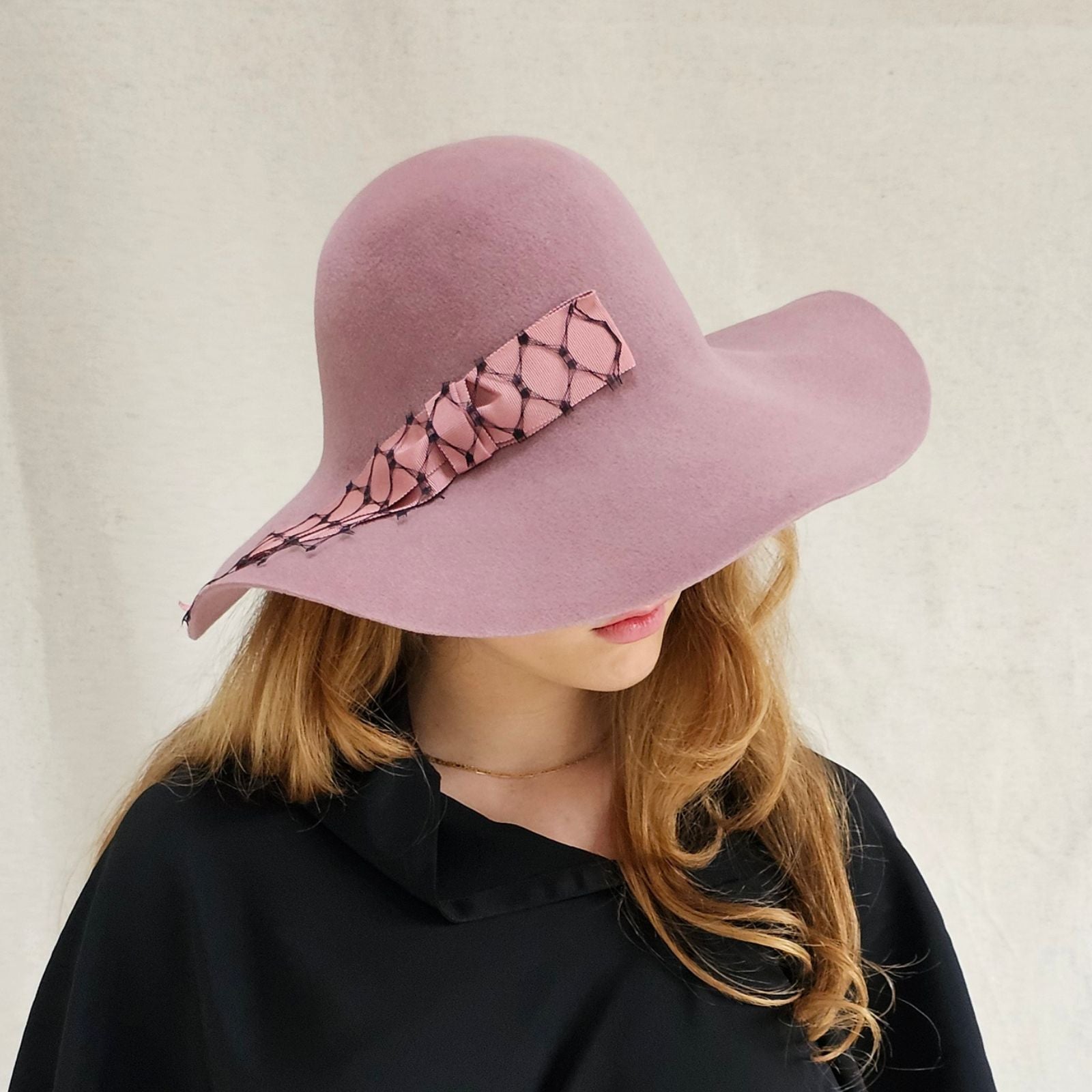 Pink felt 1970s floppy hat with elegant pink bow encased in black veiling, side view.