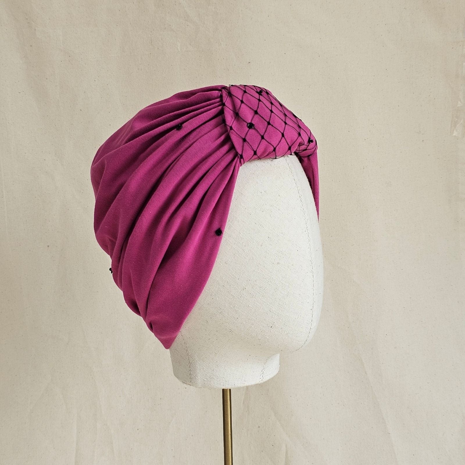Pink jersey turban with sequins and decorative veiling, angle view.