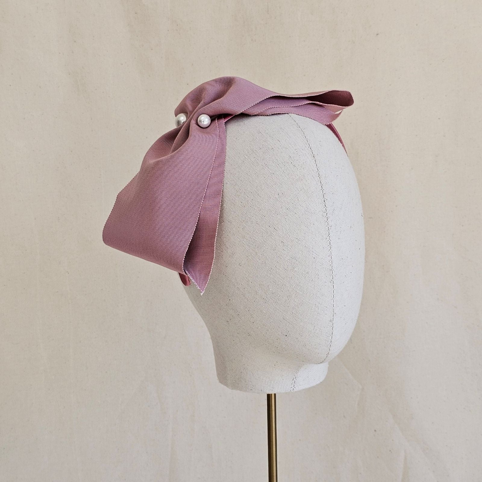 Pink wide petersham bow with 2 central pearls, on a headband.