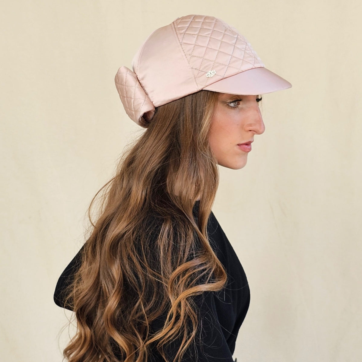 Side view of blush pink silk satin baseball cap showing quilted
panels and back bow.