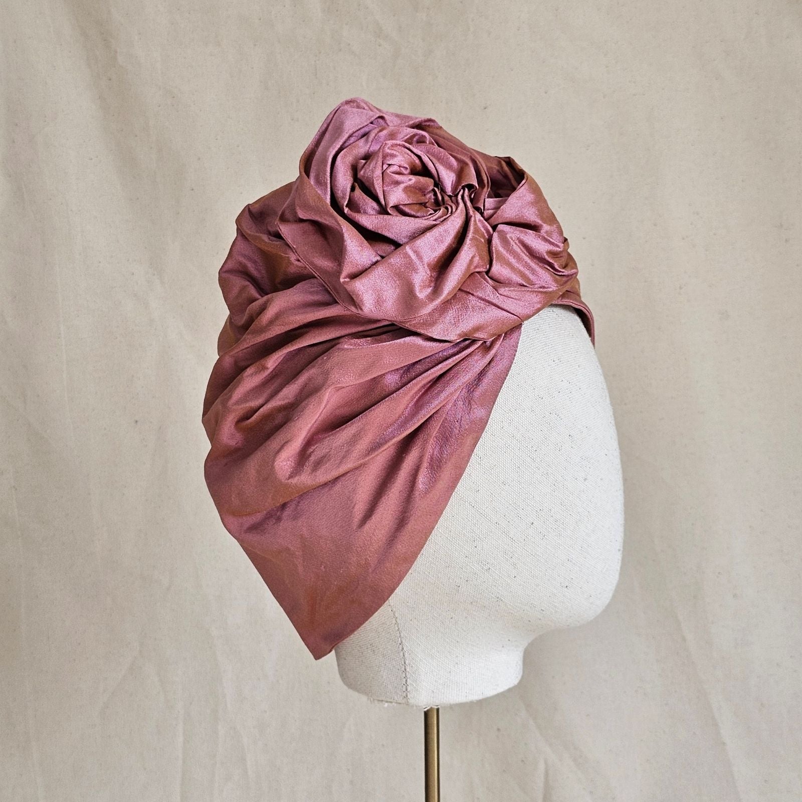 Pink silk turban with sculptural rose knot, side view.