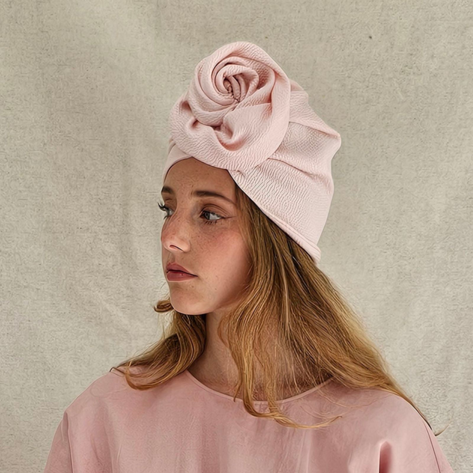 Pink silk turban loosely gathered into beautiful rose design, side view.