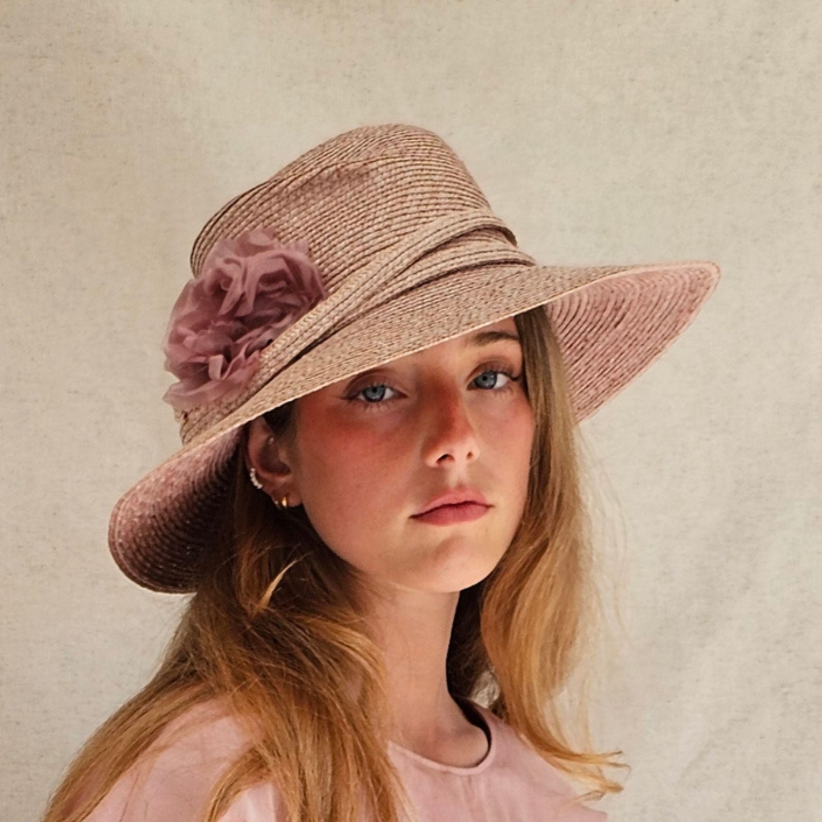 Pink straw fedora with beautiful flower embellishment, angle view.