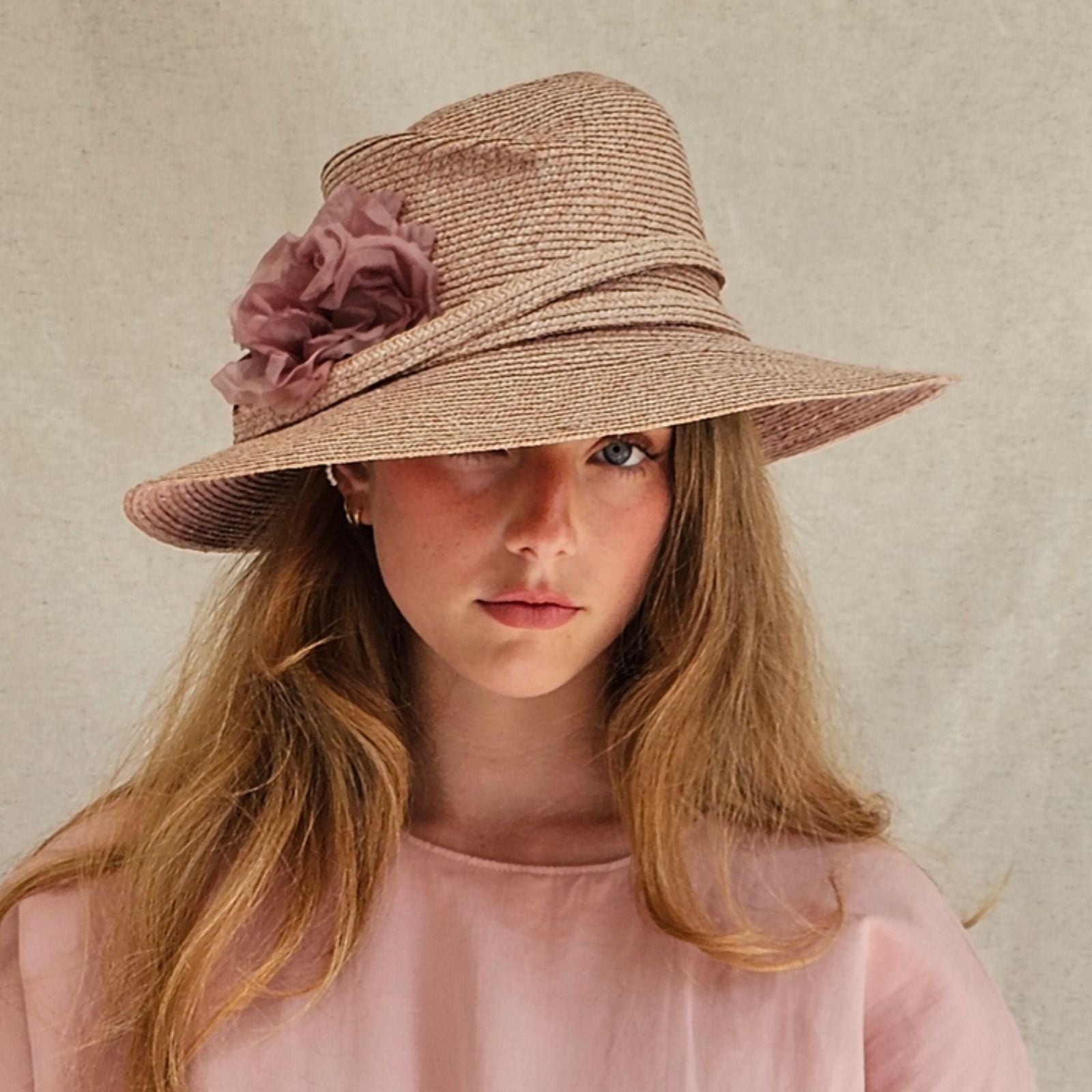 Pink straw fedora with beautiful flower embellishment, front view.