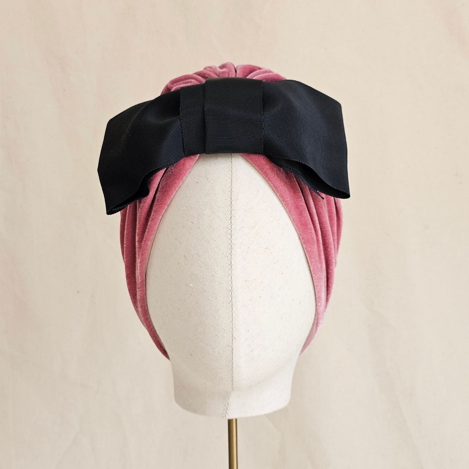 Pink velvet turban with dramatic black bow, front view.