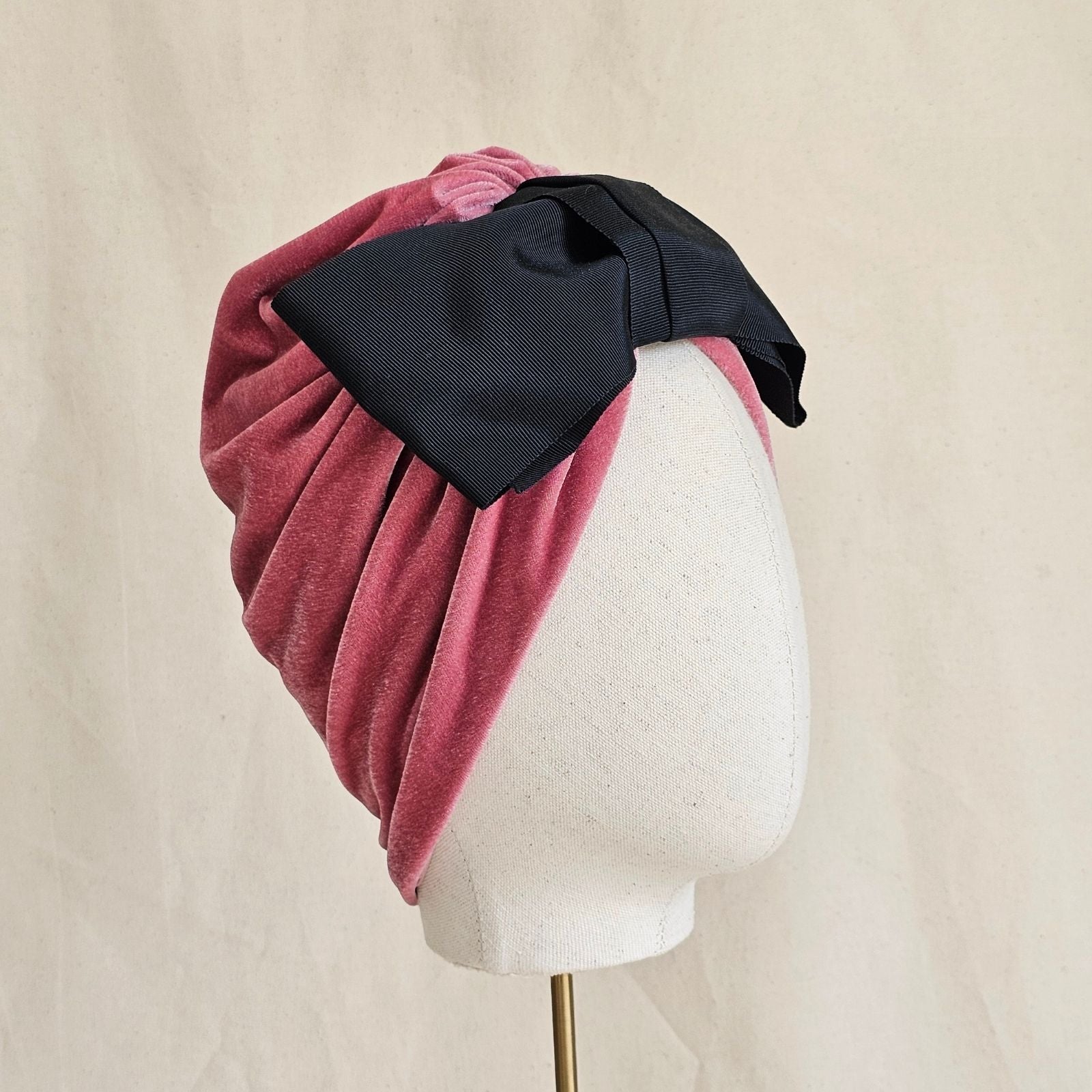 Pink velvet loosely gathered turban with dramatic black bow, side view.