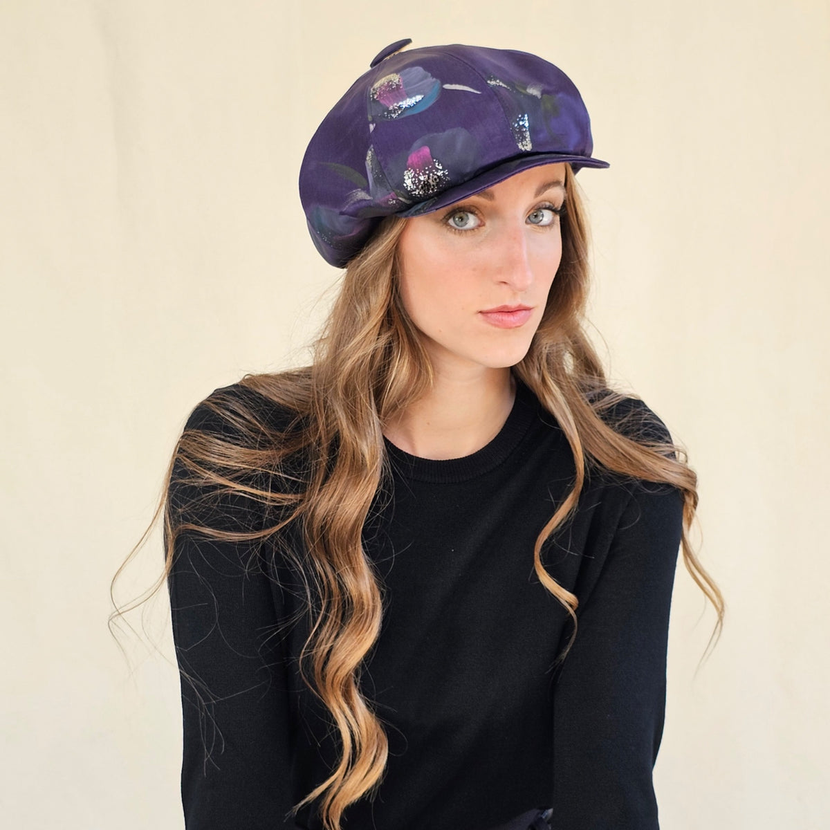 Angled view of purple hand-painted silk baker boy cap on a model.