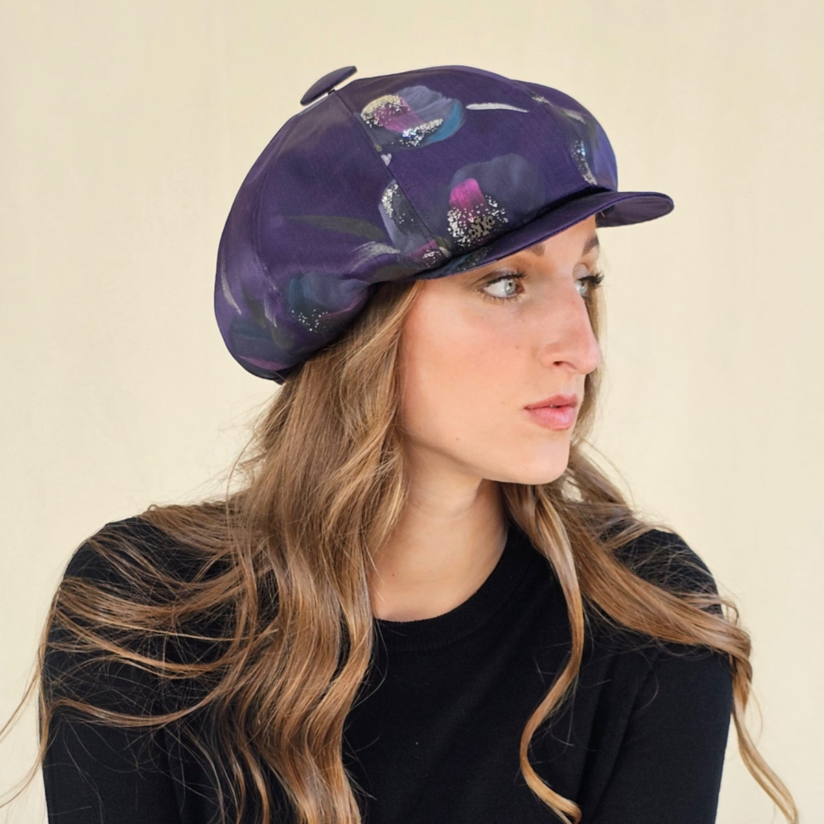 Side close-up of purple hand-painted silk baker boy cap showing
crown and peak.
