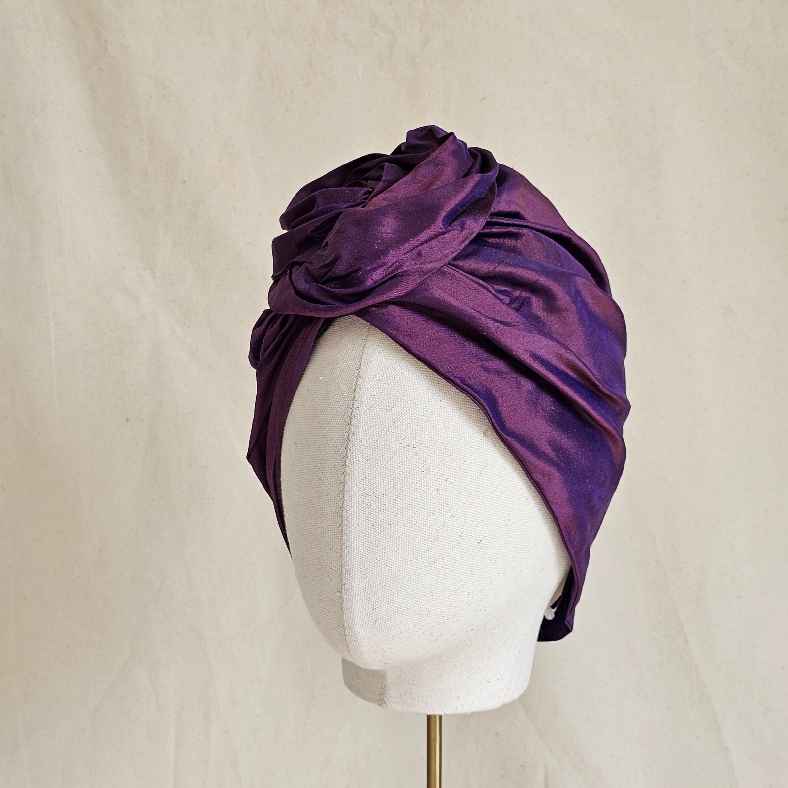 Purple silk turban with sculpted rose knot, angle view.