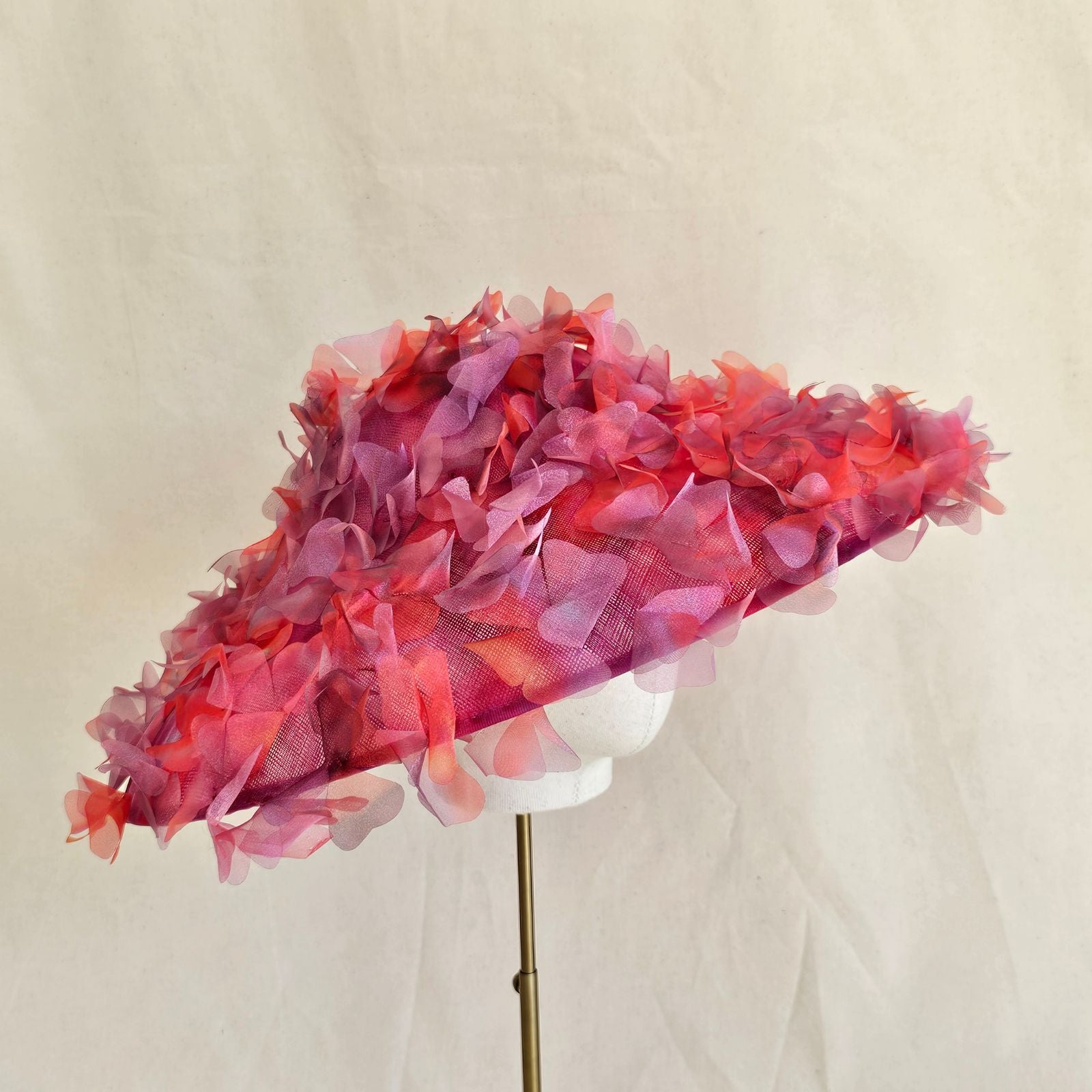 Red and pink shaded cut organza flowers on a wide brim ascot picture hat, side view.