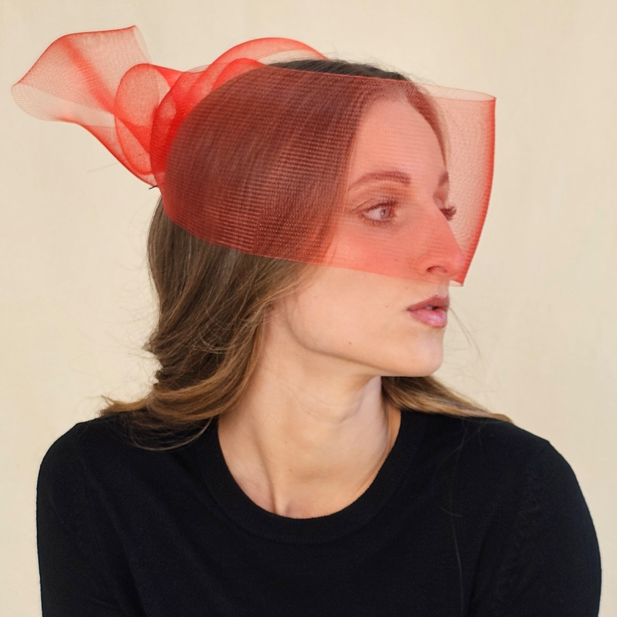 Side view of red crin face veil showing bow loops at the back.