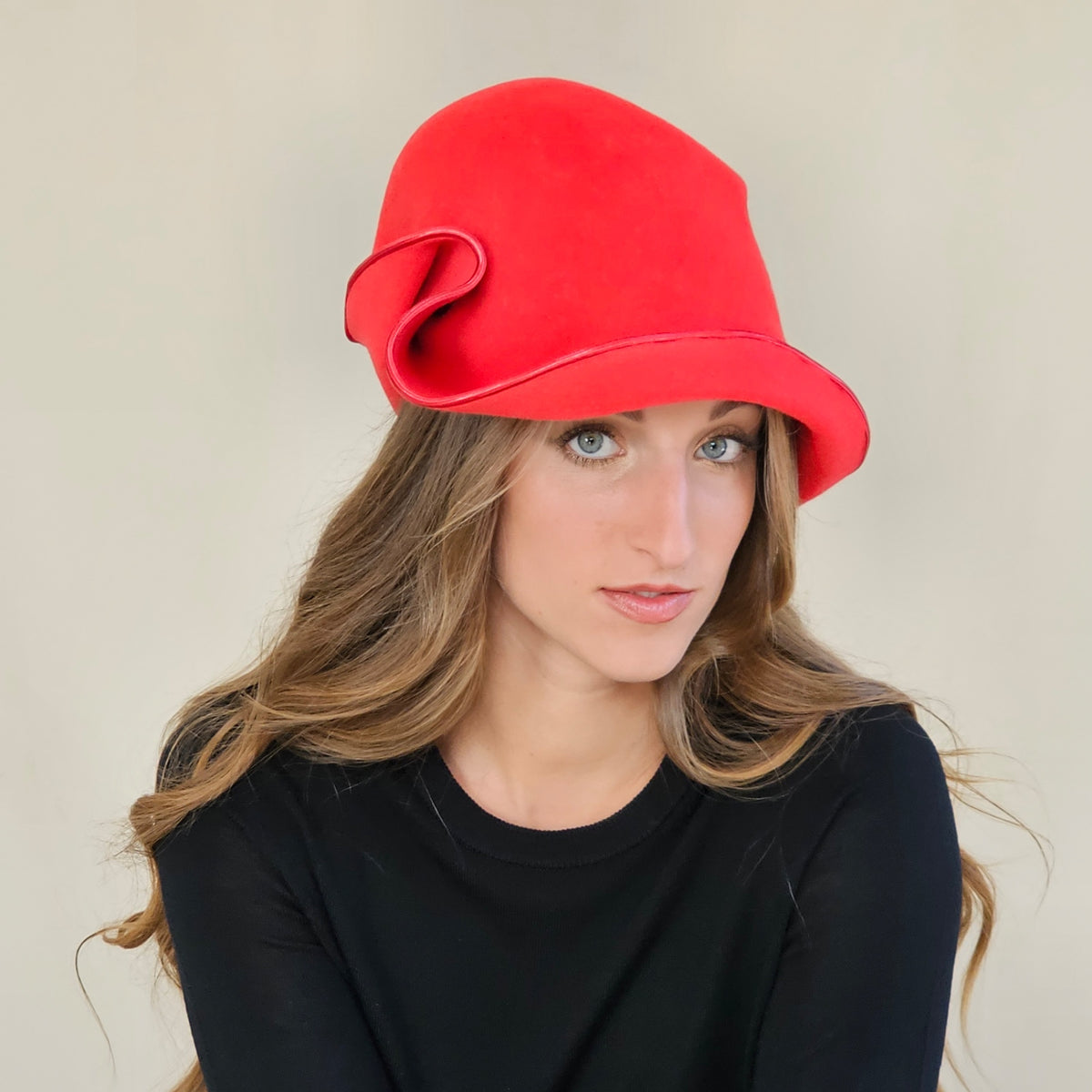 Red felt cloche with an asymmetric curled brim, worn on a model.