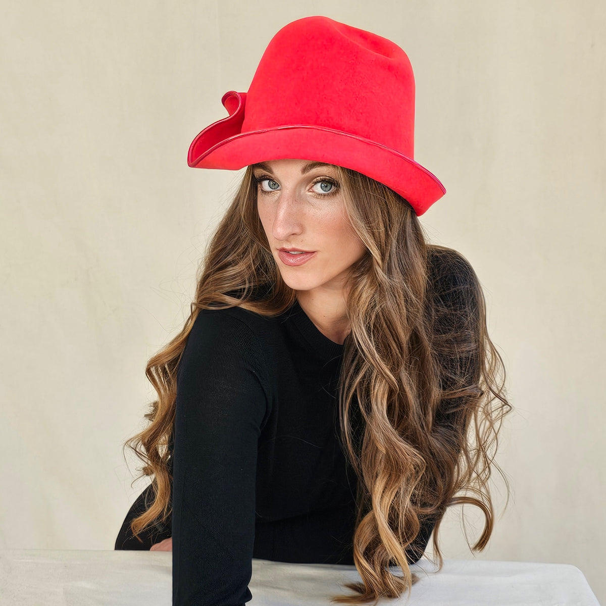 Angled view of red felt cloche showing the sculpted brim.