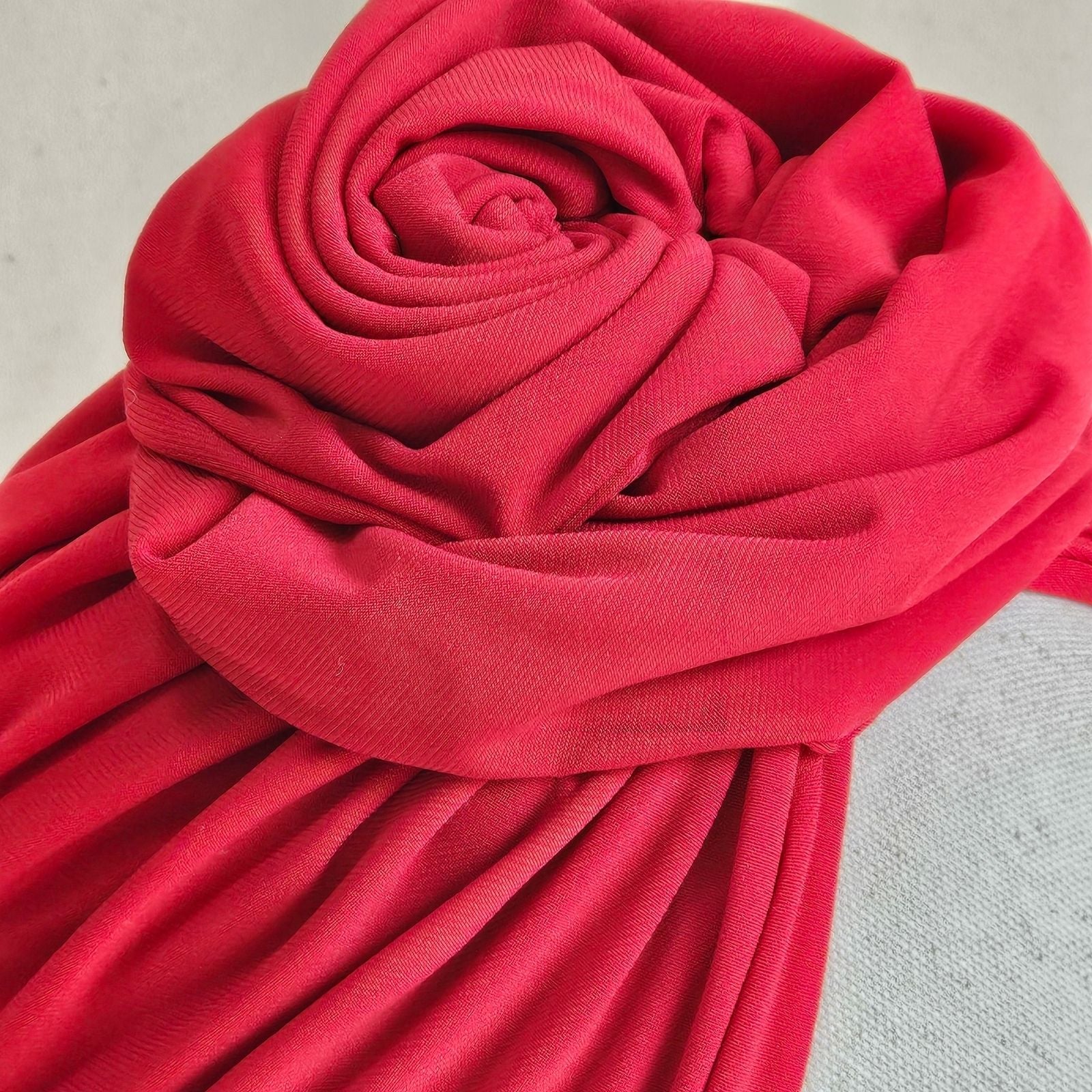 Detail of red jersey turban with intricately sculpted rose knot.