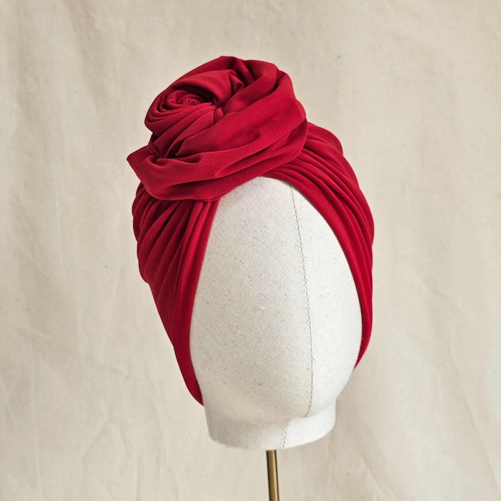 Red jersey turban gathered into sculpted intricate knotted rose, front view.