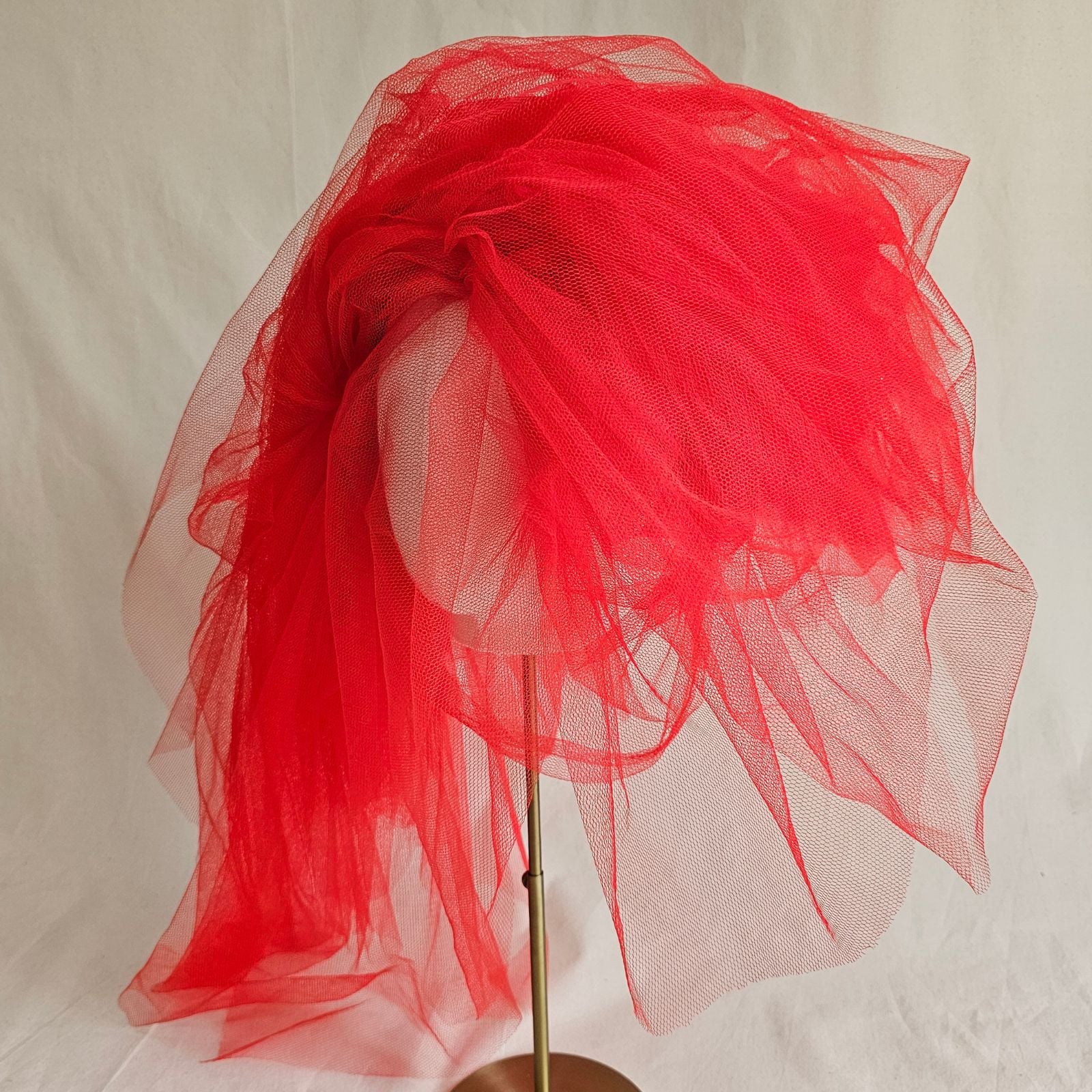 Red tulle giant statement hat, left view.