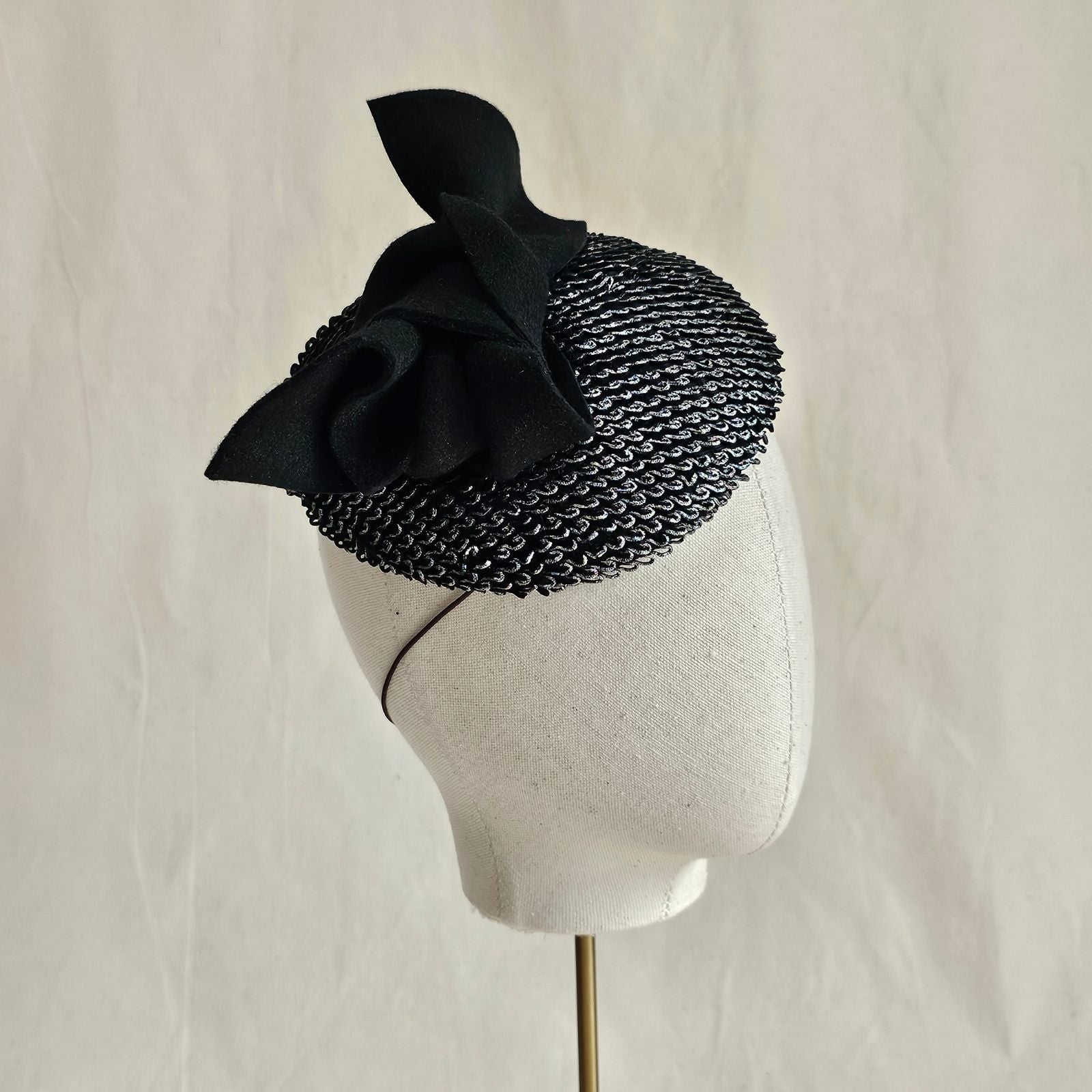 Silver black mini beret with black bow embellishment, side view.