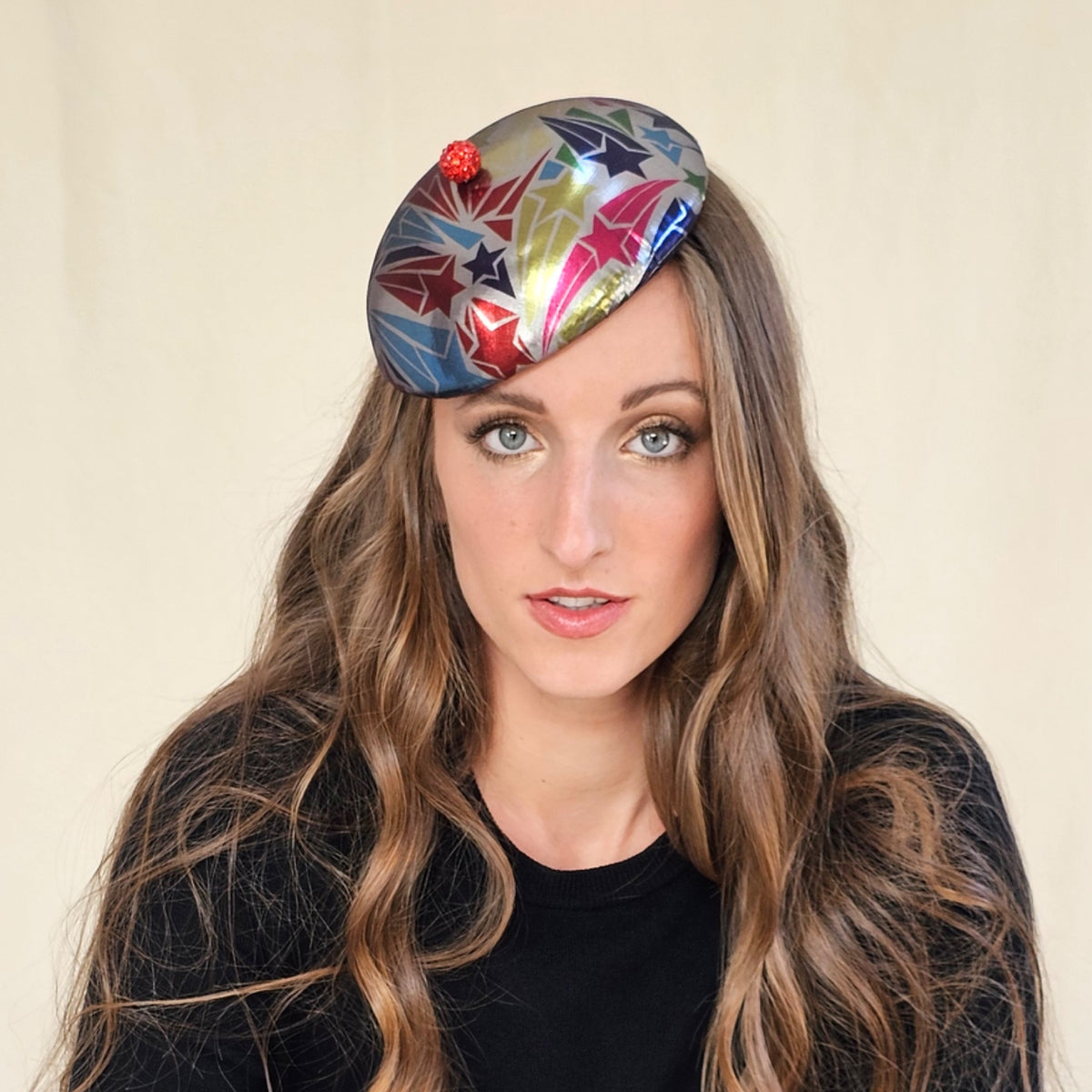 Close-up of silver beret with multicolour stars and a red globe.