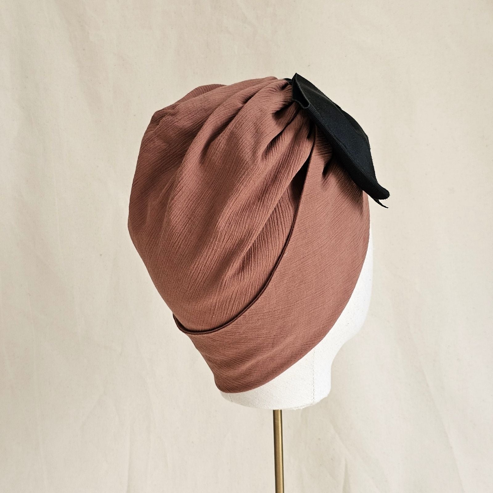 Tan cotton turban with wide black petersham bow, side view.