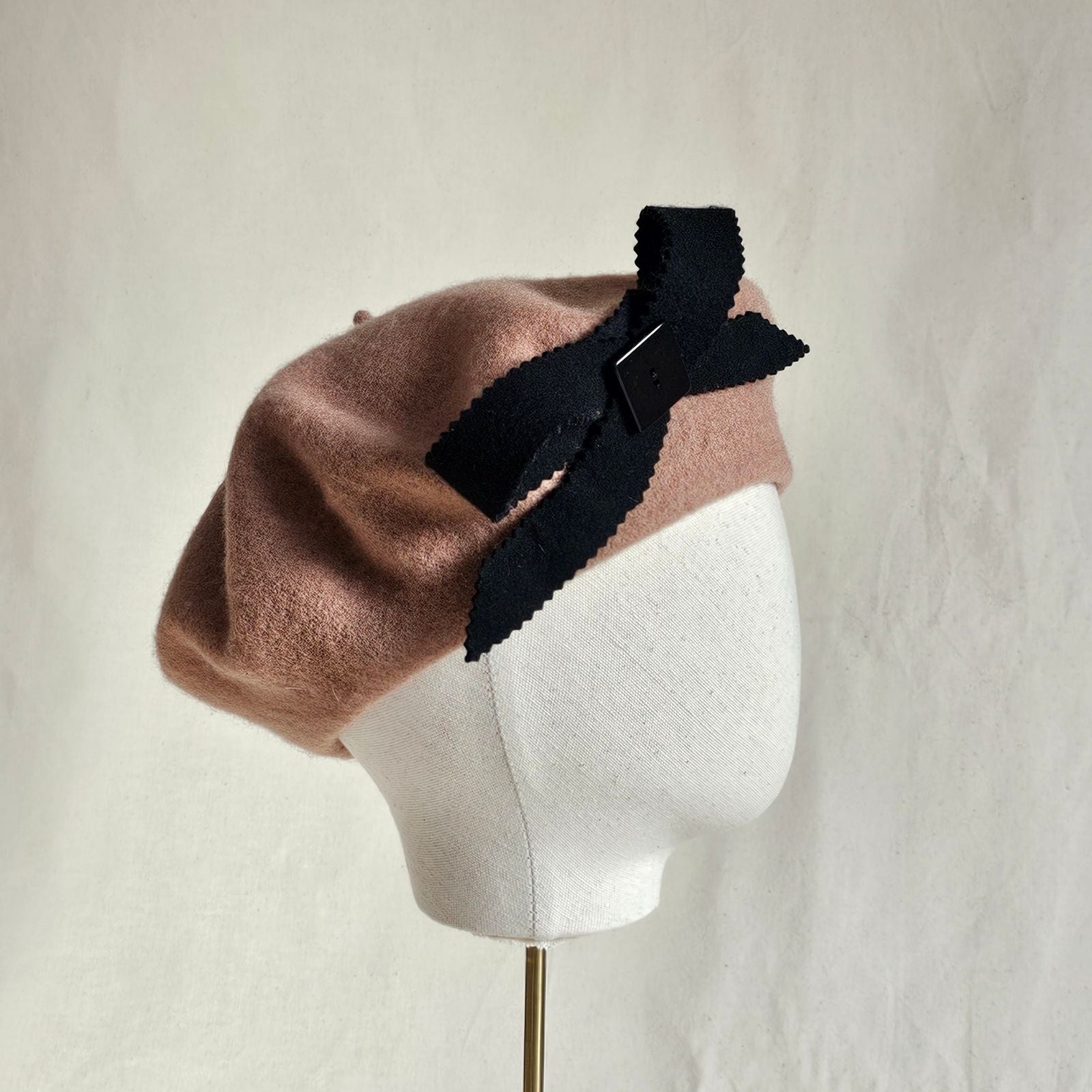 Tan wool beret with black bow embellishment, right view.
