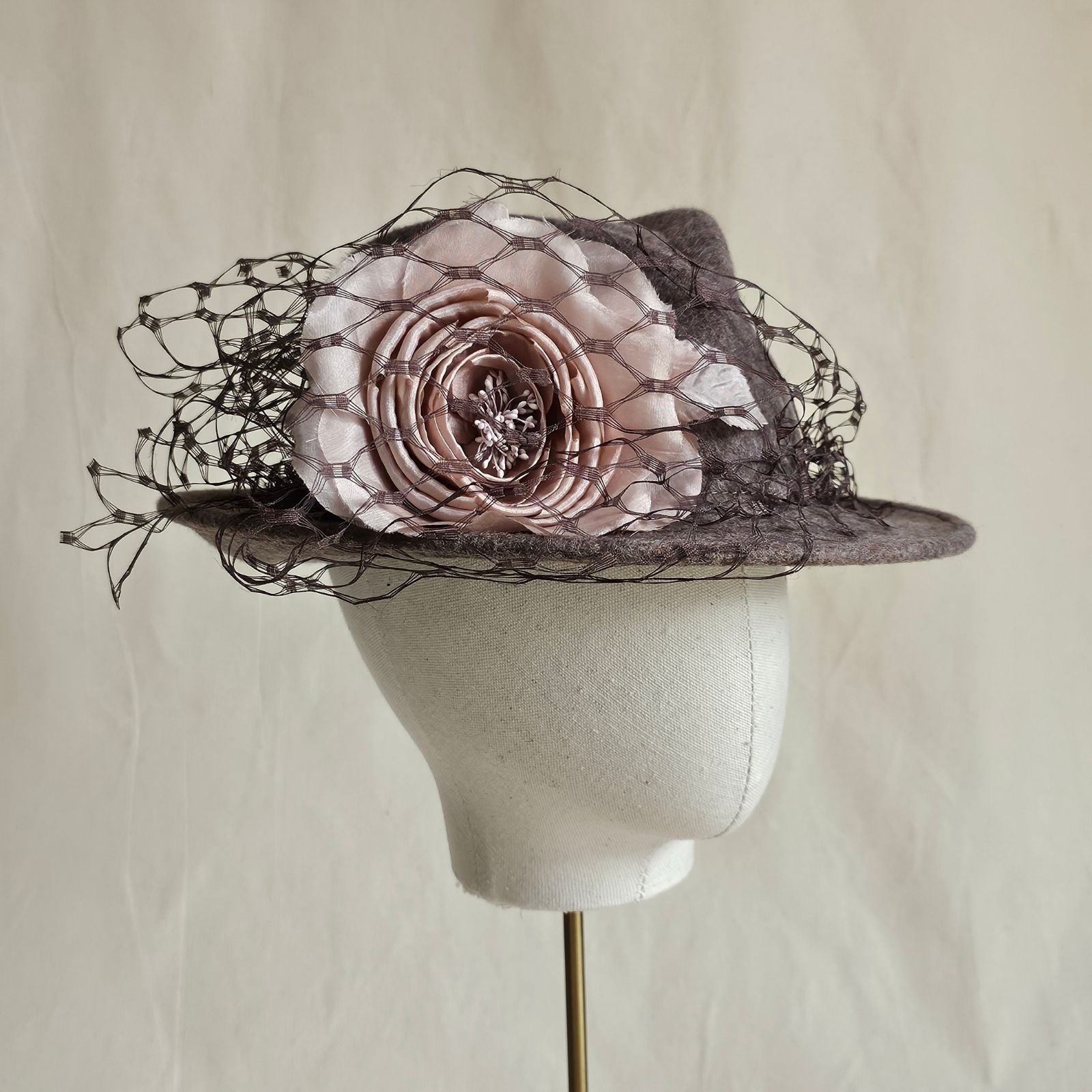 Taupe felt trilby with pink rose and black veil embellishment, angle view.