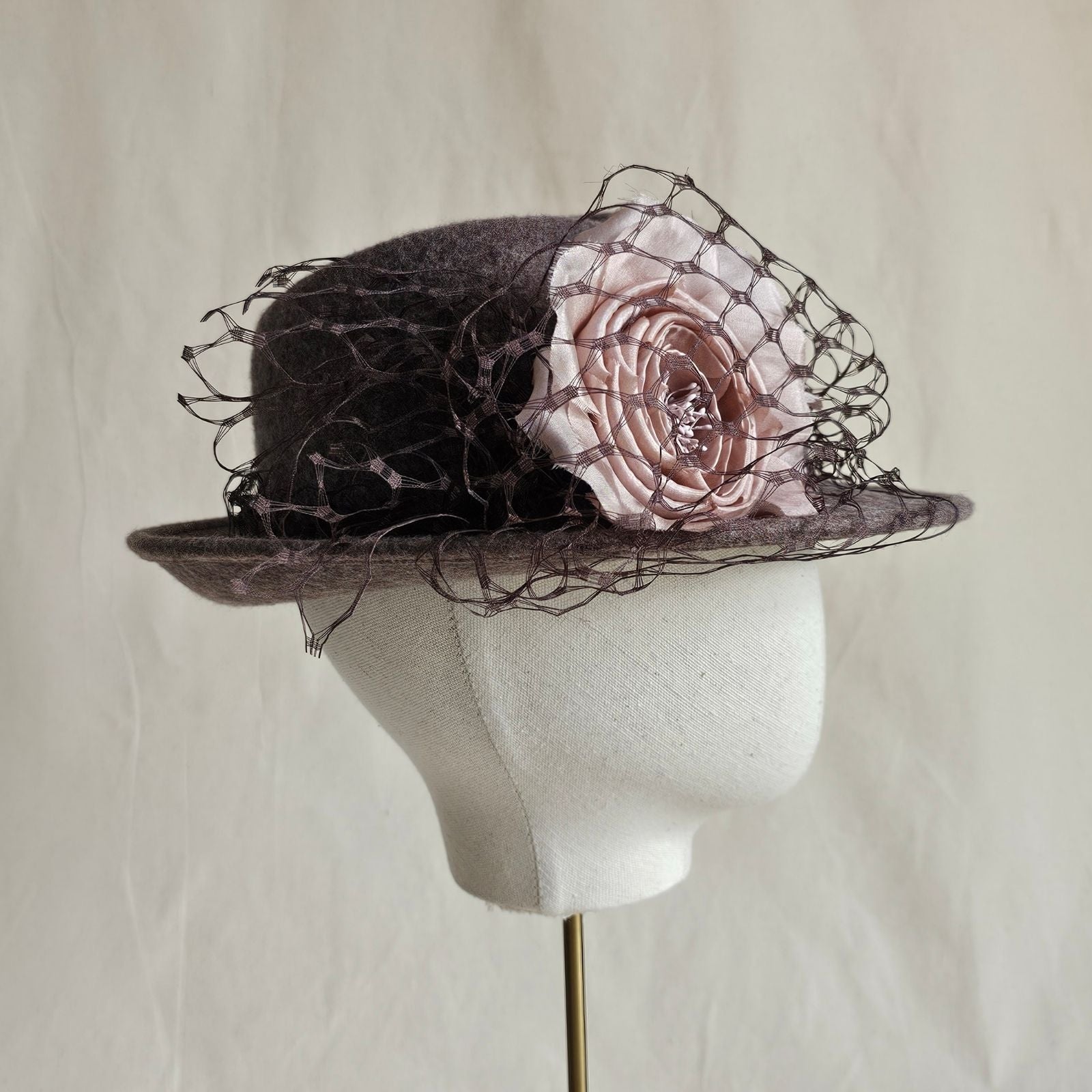 Taupe felt trilby with beautiful pink rose and black veiling, side view.