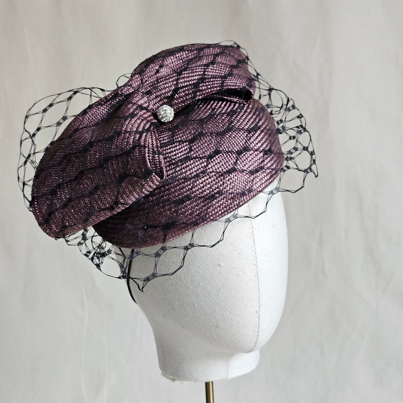 Taupe straw beret with beautiful bow and black veiling, angle view.