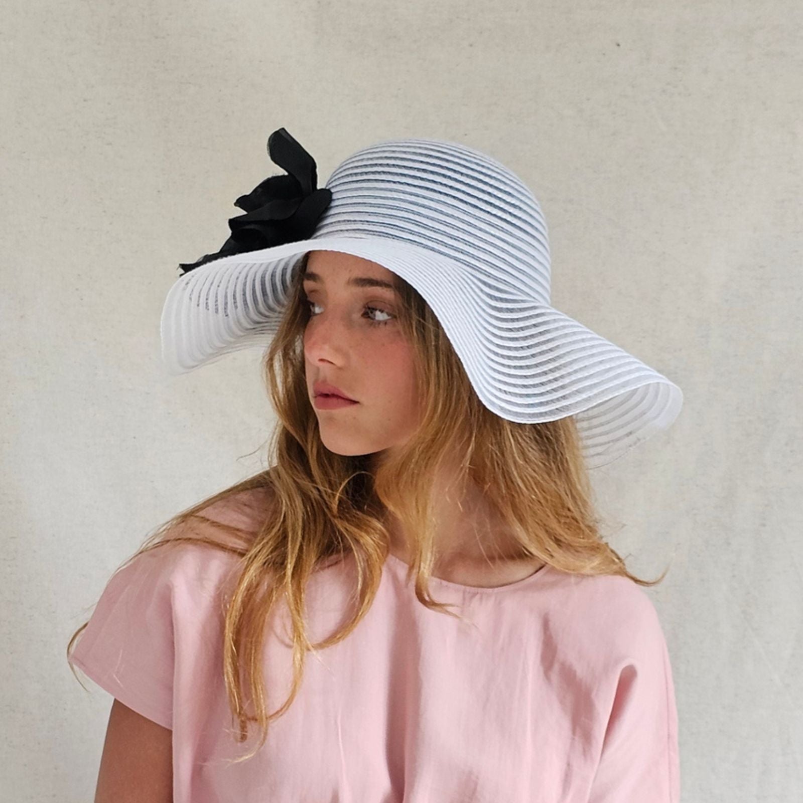 White crin floppy sunhat with dramatic black flower, side view.