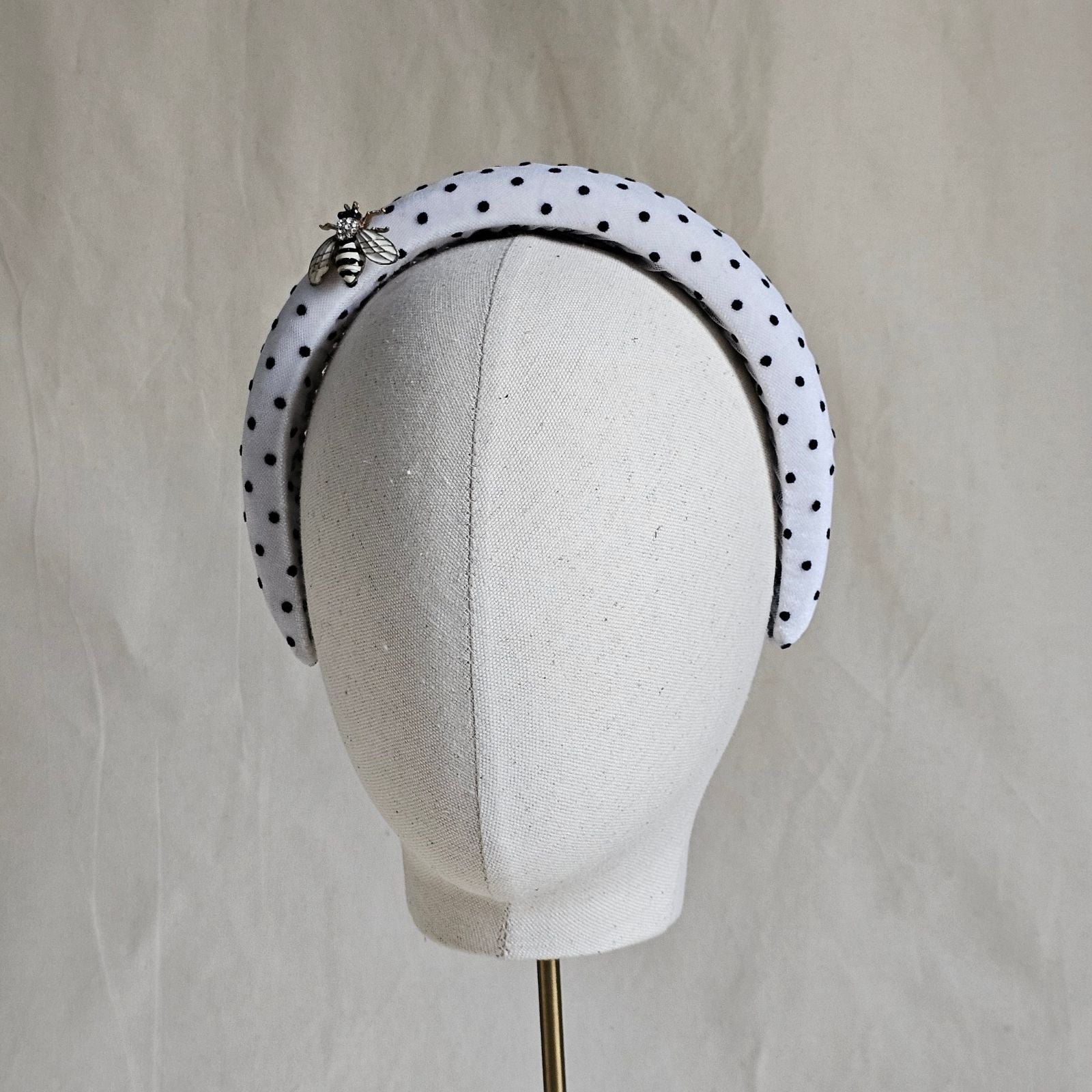 White headband with black dots and beautiful bee embellishment, front view.