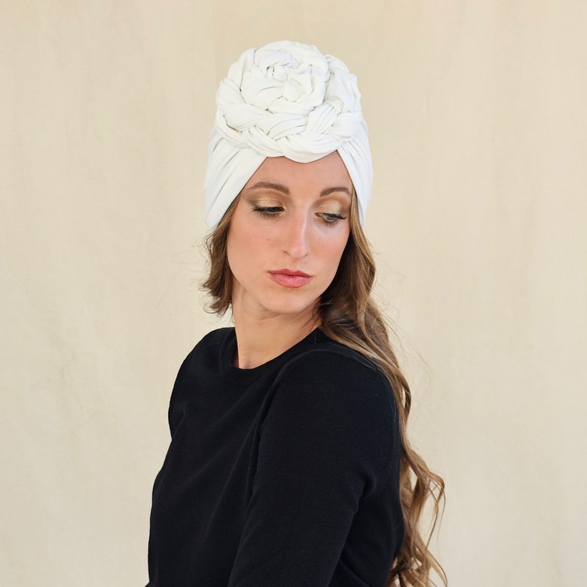 White jersey turban with a large braided rose, angled view on a
model.
