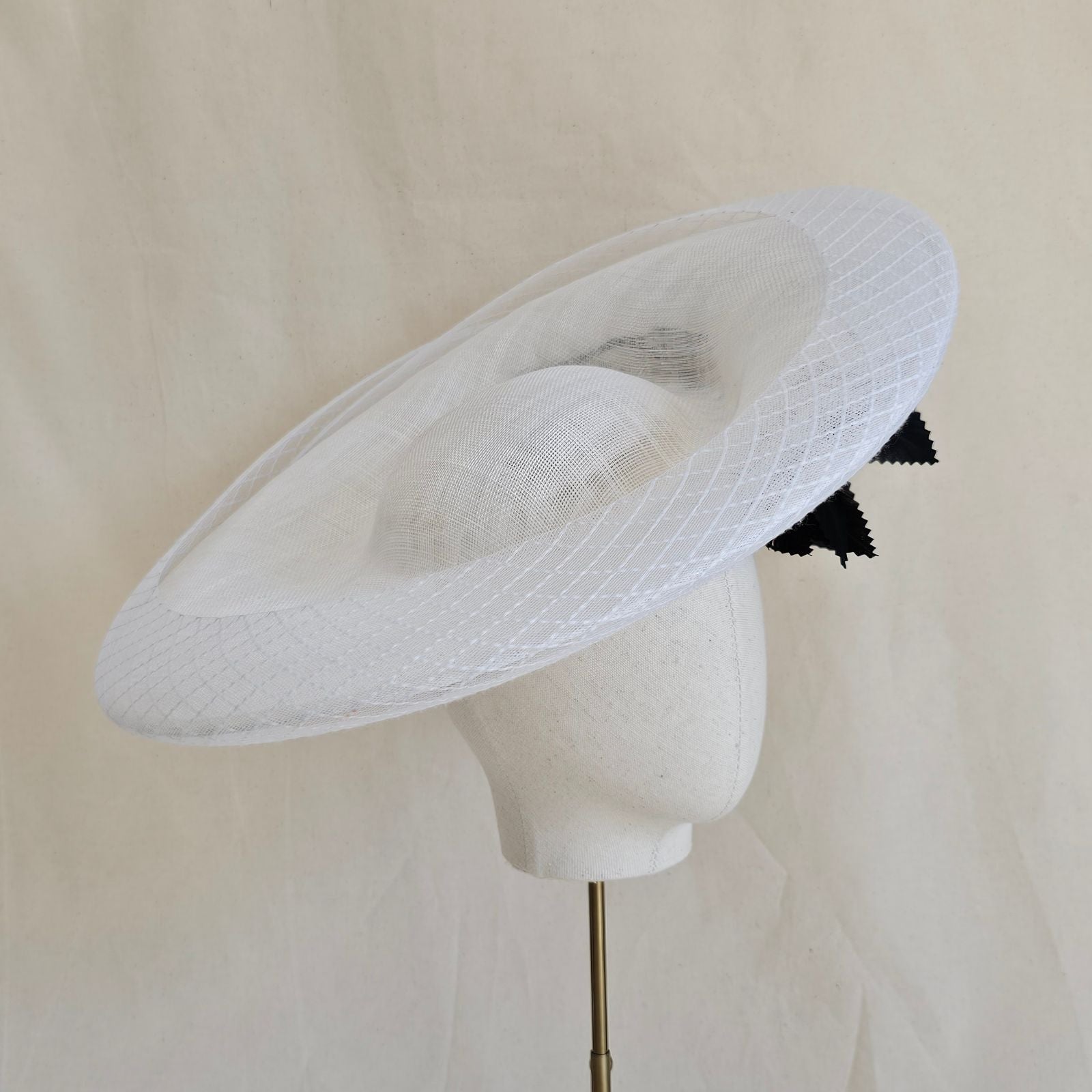 White sinamay disc hat with white check crin surround and feathers underside.